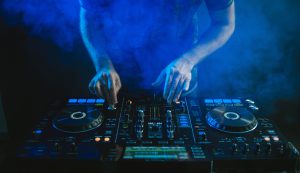 Closeup Of A Dj Working Under The Blue Lights Against A Dark Background In A Studio
